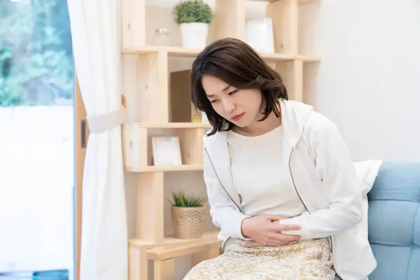 お腹をおさえる女性